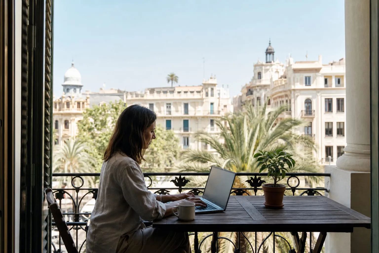 Remote worker using a laptop on a balcony above a Valencia street