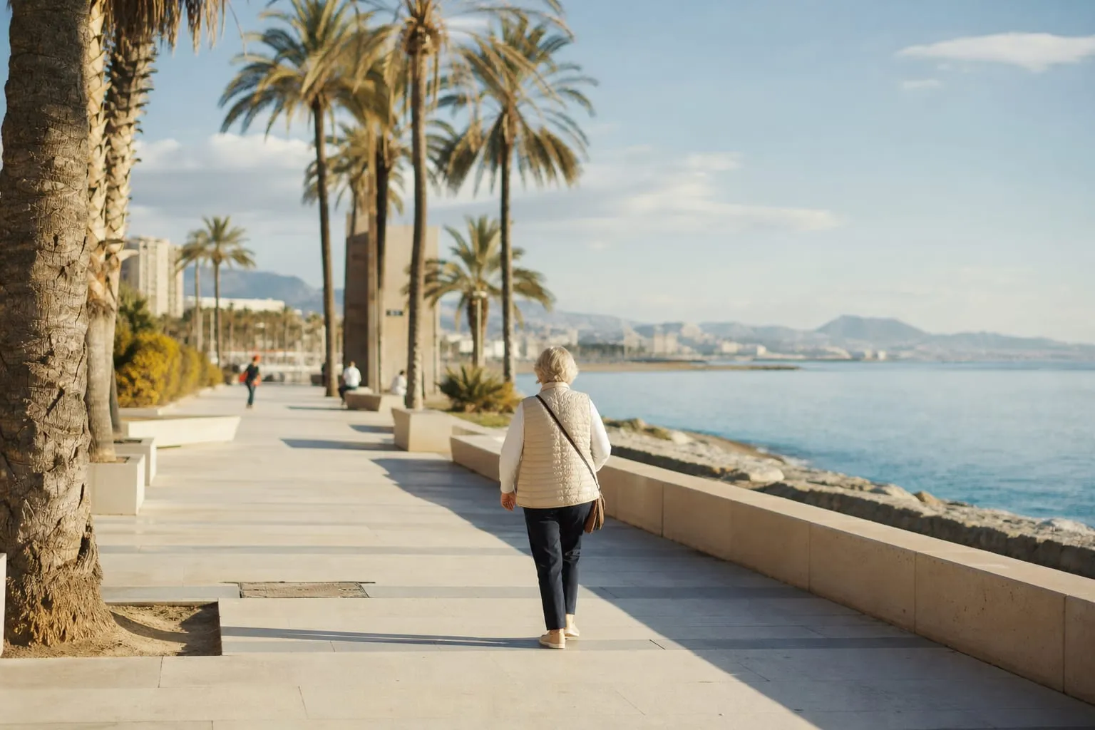 Woman walking along the Málaga seafront promenade on a winter afternoon