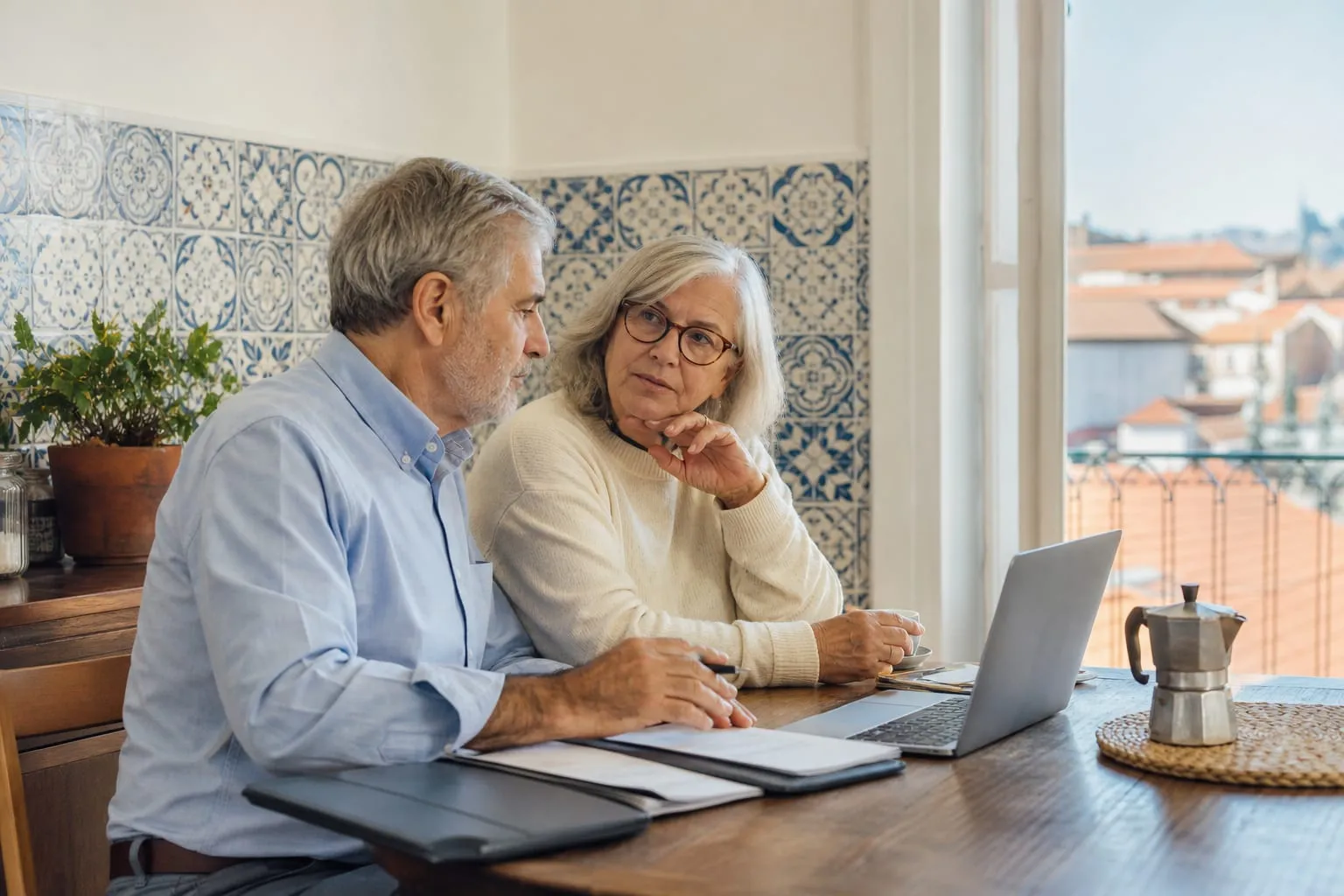 American couple sorting tax and banking paperwork at a kitchen table in a Porto apartment